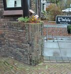 Onder de uitbouw aan de linkerhoek zit een met mondklinkers gemetselde plantenbak.
              <br/>
              Richard Keijzer, 2014